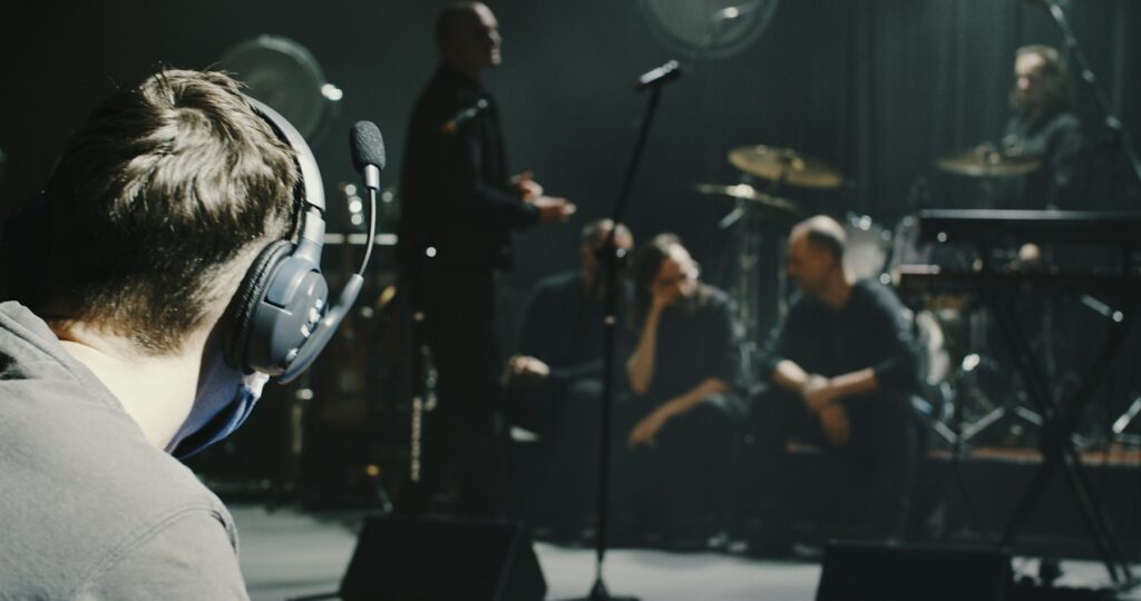 Ingénieur du son au casque face aux musiciens pendant un clip musical